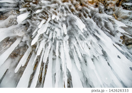 Ice icicles hanging on stone surface of cave, frozen water lake Baikal in winter 142626333