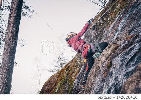 Rock climber climbing high rock wall, extreme sport outside, alpinism equipment 142626410