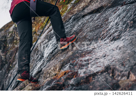 Rock climber climbing high rock wall, extreme sport outside, alpinism equipment Rock climber climbing high rock wall, extreme sport outside, alpinism equipment 142626411