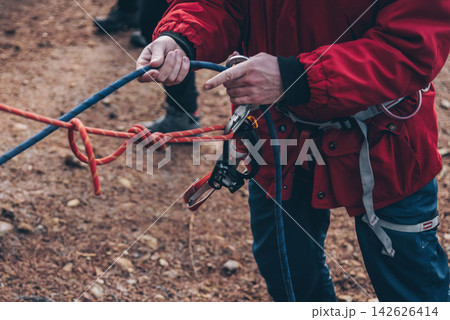 Rock climber tying knot on rope for climber, man preparing climbing equipment 142626414