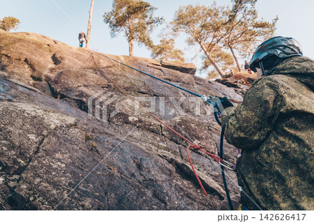 Rock climber climbing high rock wall, extreme sport outside, alpinism equipment Rock climber climbing high rock wall, extreme sport outside, alpinism equipment 142626417