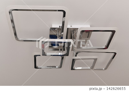 Modern chandelier illuminates minimalist room. 142626655