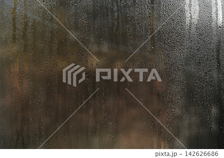 Close-up of water droplets on glass window, creating an abstract background effect. 142626686