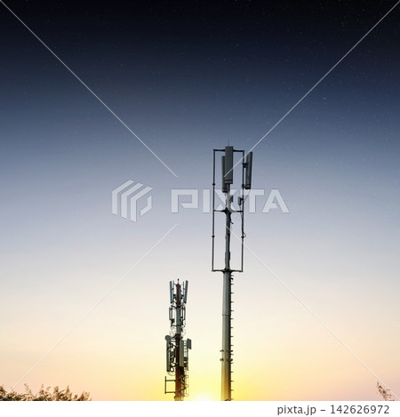 Two cellular towers silhouetted against a gradient sunset sky transitioning to night with visible stars. Concept of communication network and connection technology 142626972