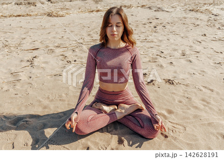 Woman doing yoga on sandy beach, female sport background sea blue sky, sunny day 142628191