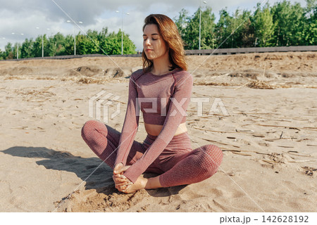 Woman doing yoga on sandy beach, female sport background sea blue sky, sunny day 142628192