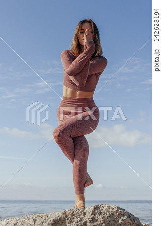 Woman doing yoga on sandy beach, female sport background sea blue sky, sunny day Woman doing yoga on sandy beach, female sport background sea blue sky, sunny day 142628194