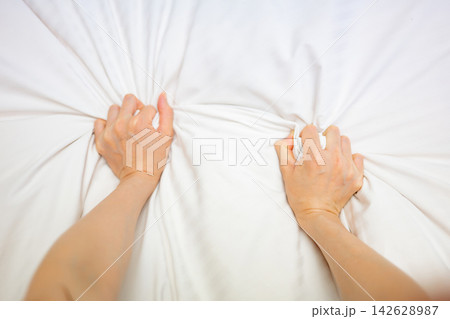 ベッドでシーツを握り締める女性 ベッドでシーツを握り締める女性 142628987