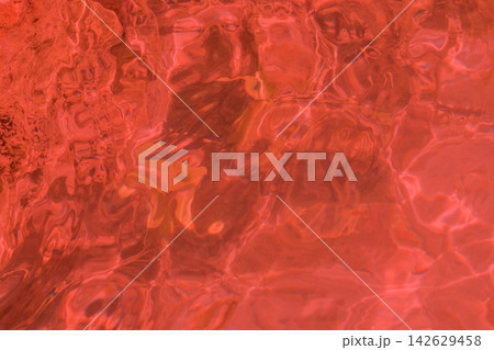 Textured surface of shimmering red water with reflections and ripples, creating a vibrant and dynamic visual effect in a natural aquatic environment Textured surface of shimmering red water with reflections and ripples, creating a vibrant and dynamic visual effect in a natural aquatic environment 142629458