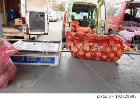 Market scene with scales and bag of onions in vendor area during daytime at local market Market scene with scales and bag of onions in vendor area during daytime at local market 142629995
