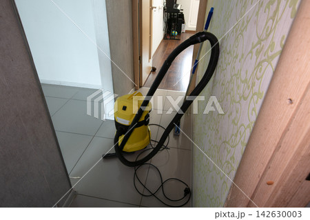Vacuum cleaner stands in hallway during cleaning process in a home at daytime with sunlight coming through the door Vacuum cleaner stands in hallway during cleaning process in a home at daytime with sunlight coming through the door 142630003