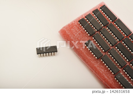 Microchips on red foam. Chip packaging. Microchips in a DIP package. 142631658