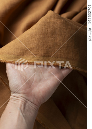 Hand Holding Rust Brown Linen Fabric 142632701