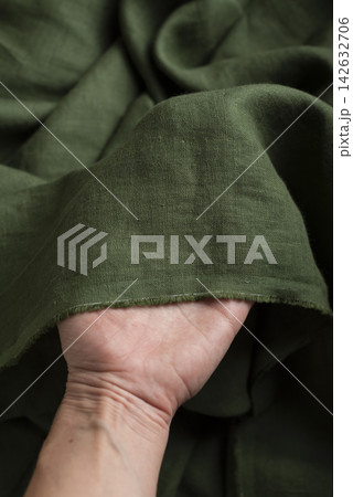 Hand Holding Olive Green Linen Fabric Edge Hand Holding Olive Green Linen Fabric Edge 142632706
