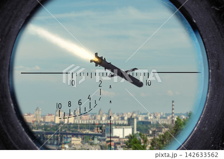 Flying cruise missile seen through an optical military sight against an urban city background. 142633562