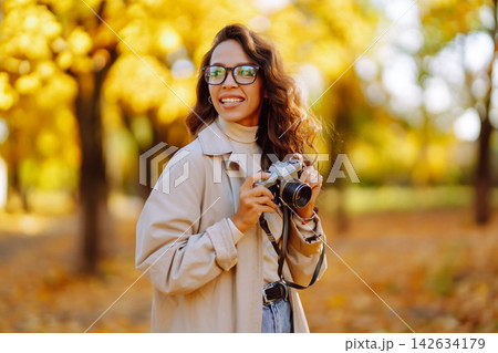 Beautiful woman taking pictures in the autumn forest. Rest, relaxation, tourism, lifestyle concept. Beautiful woman taking pictures in the autumn forest. Rest, relaxation, tourism, lifestyle concept. 142634179