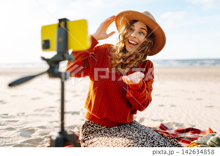 Style woman using smartphone with stabilizer, taking pictures in on sea beach. Woman creates content Style woman using smartphone with stabilizer, taking pictures in on sea beach. Woman creates content 142634858