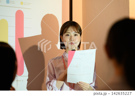 会議で資料を手に持ちプレゼンを行う女性社員 会議で資料を手に持ちプレゼンを行う女性社員 142635227