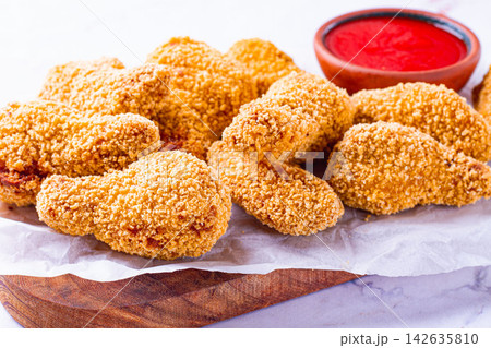 fried chicken legs in breadcrumbs, on a wooden chopping board, with red sauce, no people, 142635810