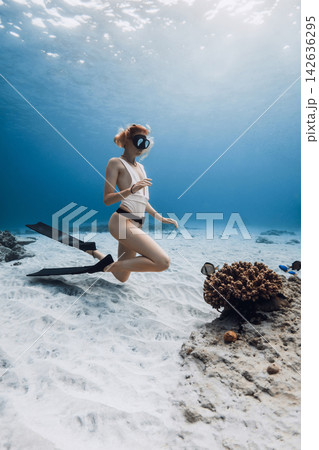 Female free diver with fins underwater posing on sandy bottom Female free diver with fins underwater posing on sandy bottom 142636295