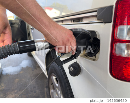 Person refueling a car at a gas station amid rising fuel prices Person refueling a car at a gas station amid rising fuel prices 142636420