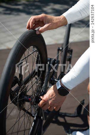 Cyclist checking road bike rear wheel before ride Cyclist checking road bike rear wheel before ride 142637104