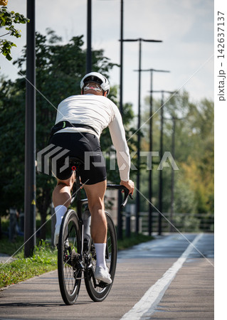Male road cyclist riding away on bike path 142637137