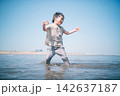 夏の海の浅瀬で貝殻を手に笑う男の子のローアングル 142637187