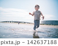 夏の海の浅瀬を服のまま歩いて水遊びする男の子 142637188