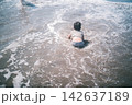 夏の海の波打ち際で腹ばいになって遊ぶ子どもの後ろ姿 142637189