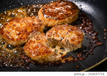 鉄板で焼きたてのハンバーグ、ジューシーな肉汁とこんがり焦げ目が食欲をそそる調理風景 鉄板で焼きたてのハンバーグ、ジューシーな肉汁とこんがり焦げ目が食欲をそそる調理風景 142637718