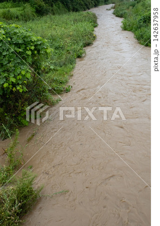 大雨で増水した濁った川の流れ 大雨で増水した濁った川の流れ 142637958