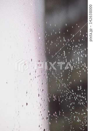 Raindrops on window screen mesh with soft light contrast and bokeh Raindrops on window screen mesh with soft light contrast and bokeh 142638000