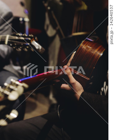 Concert view of acoustic electric guitar player with vocalist and rock band performing in a club, male musician guitarist on stage with audience in a crowded concert club hall arena, hands on guitar 142640537