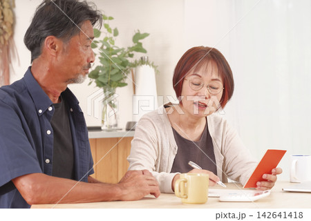年金手帳を見ながら老後の相談をする夫婦 年金手帳を見ながら老後の相談をする夫婦 142641418