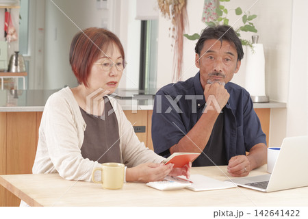 年金手帳を見ながら老後の暮らしを相談する夫婦 142641422