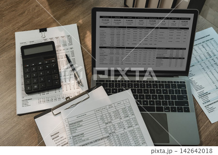 Laptop dashboard, calculator, financial reports, clipboard on desk for invoice review, receipt  142642018