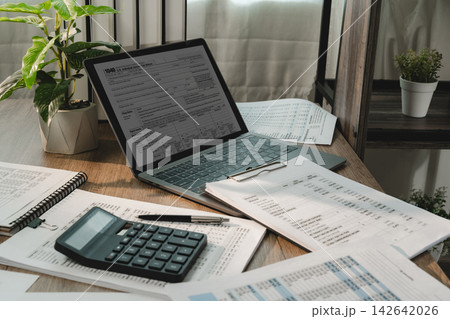 Tax preparation workspace with tax form on laptop, Tax preparation workspace with tax form on laptop, 142642026