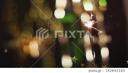 Sparkling sparkler stem emitting sparks at night, with star confetti and bokeh lights, copy space Sparkling sparkler stem emitting sparks at night, with star confetti and bokeh lights, copy space 142642183