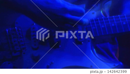 Strumming guitarist hands pressing strings on neck, as blue stage lights coming on, showing pickups 142642399