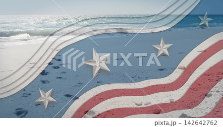 Showing sandy shoreline with footprints, pebbles at shore, overlaying red-white stripes and stars 142642762