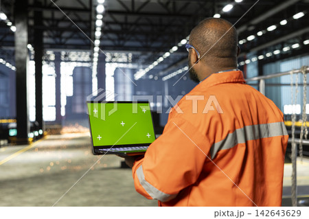 Isolated screen on laptop with african american staff handles heavy machinery during production, showing industrial focus and manpower. Manufacturing plant with sparks on factory floor. Isolated screen on laptop with african american staff handles heavy machinery during production, showing industrial focus and manpower. Manufacturing plant with sparks on factory floor. 142643629