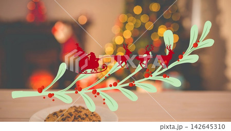 Displaying pale green sprig and red Santa sleigh overlay on tabletop at home, with chocolate cookie Displaying pale green sprig and red Santa sleigh overlay on tabletop at home, with chocolate cookie 142645310