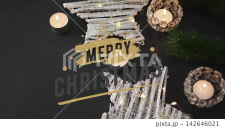 Shining star ornaments lying on black table, with tealight pine sprig fairy lights Merry Christmas 142646021