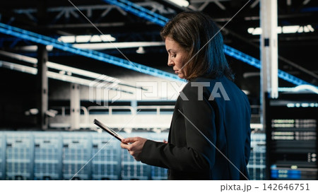 Data center engineer configuring rigs using augmented reality control panel. Woman walking in server farm, interacting with virtual holographic visualization to adjust hardware settings Data center engineer configuring rigs using augmented reality control panel. Woman walking in server farm, interacting with virtual holographic visualization to adjust hardware settings 142646751