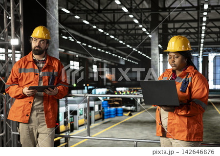 African american personnel with helmet examining machinery hall activity, ensuring safety and productivity standards within heavy industry plant. Construction on large-scale equipment. African american personnel with helmet examining machinery hall activity, ensuring safety and productivity standards within heavy industry plant. Construction on large-scale equipment. 142646876