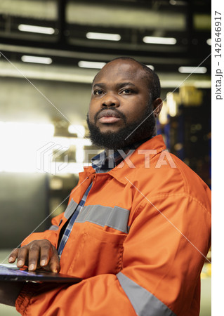 African american male monitoring package tracking on laptop. Warehouse operations rely on accurate inventory control, delivery planning and transportation for large business shipping networks. African american male monitoring package tracking on laptop. Warehouse operations rely on accurate inventory control, delivery planning and transportation for large business shipping networks. 142646917