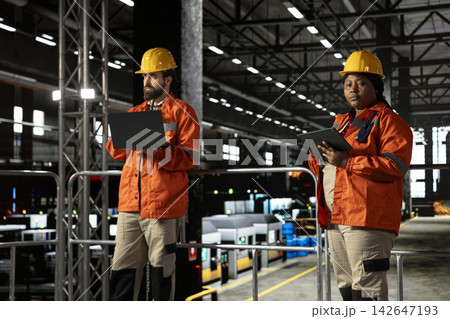 African american engineer, checking factory floor, heavy equipment, industrial space filled with steel work and mechanical systems reflecting the scale of heavy industry production. African american engineer, checking factory floor, heavy equipment, industrial space filled with steel work and mechanical systems reflecting the scale of heavy industry production. 142647193