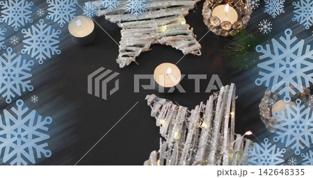 Glowing whitewashed twig stars sparkling on dark table, with tealights, pine, blue snowflakes 142648335