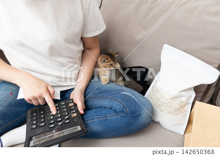 Pet expense budgeting at home with a cat and calculator planning costs 142650368